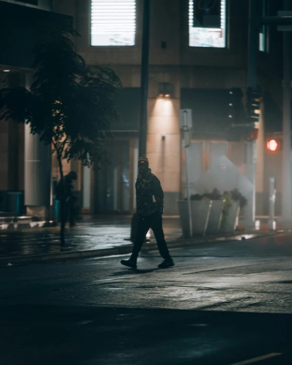 a man walking across an empty city street at night