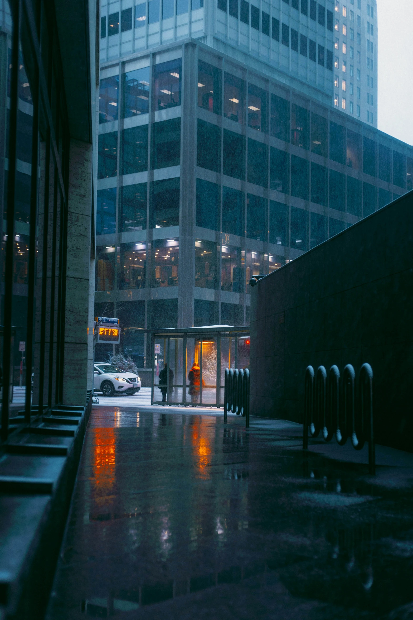 rainy view of a dark looking city street with building in the background