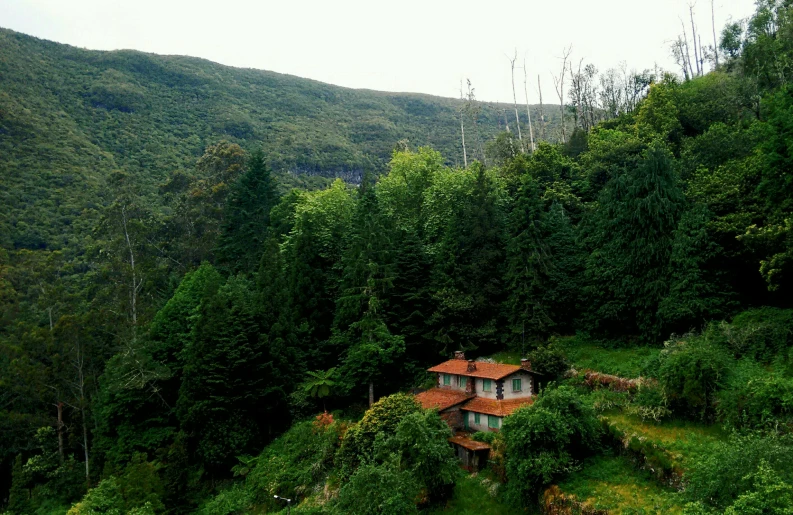 a house sits on the edge of a lush green valley