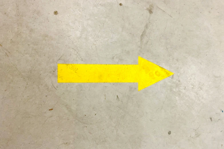 yellow arrow sign on the ground indicating where