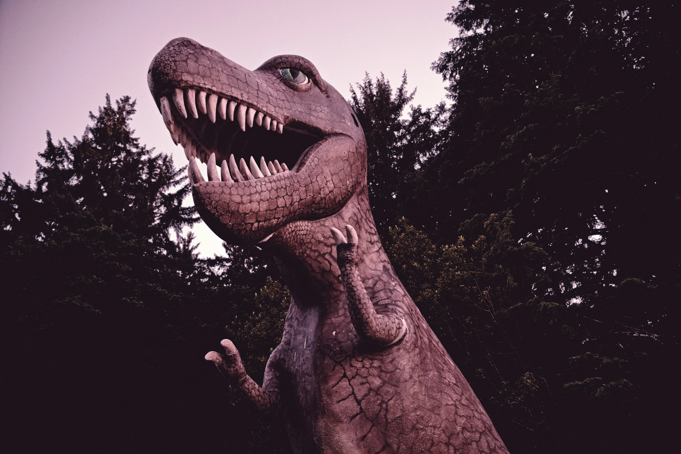 a large fake t - rex is in front of some trees