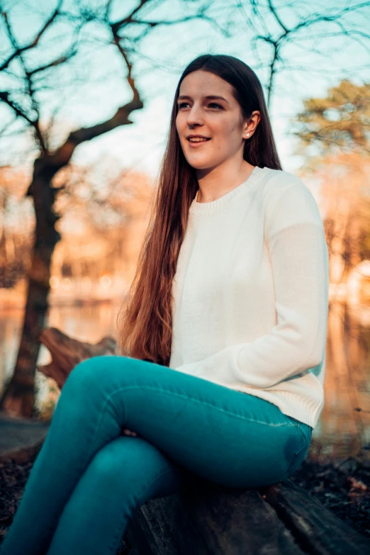 a woman sitting on top of a wooden bench in front of a tree