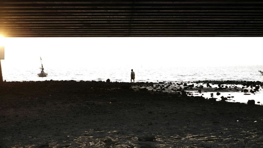 a man is standing at the water's edge, looking out into the ocean