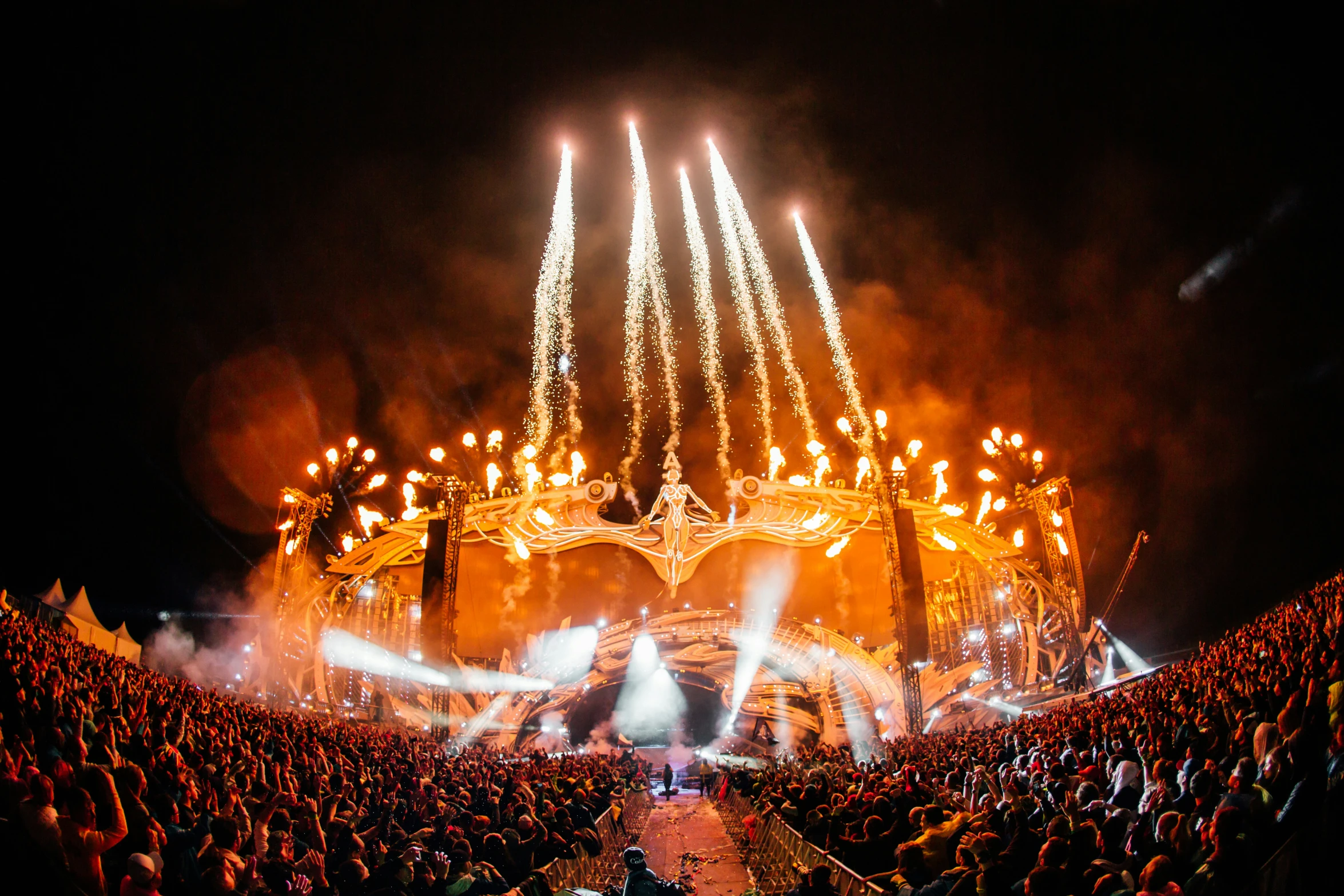 a large crowd stands at the front of a lit stage