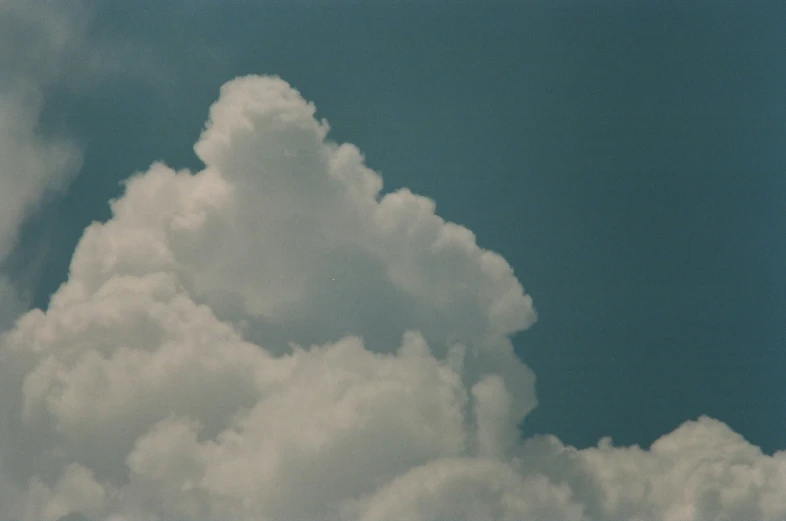 a plane flying in the blue sky with some clouds