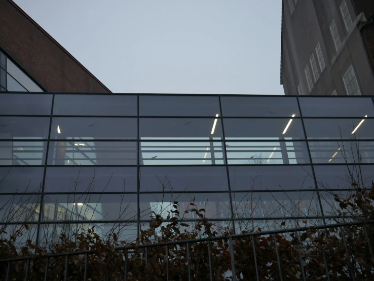 an empty glass building with an iron gate and a clock on it