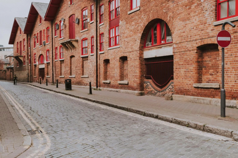 a red brick building along a street with several windows