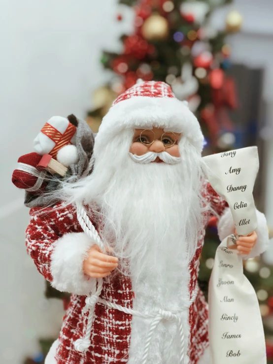 a figurine holding a santa clause next to a christmas tree