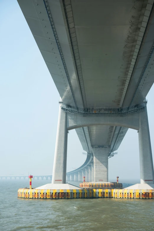 two watercrafters are under a bridge crossing the ocean