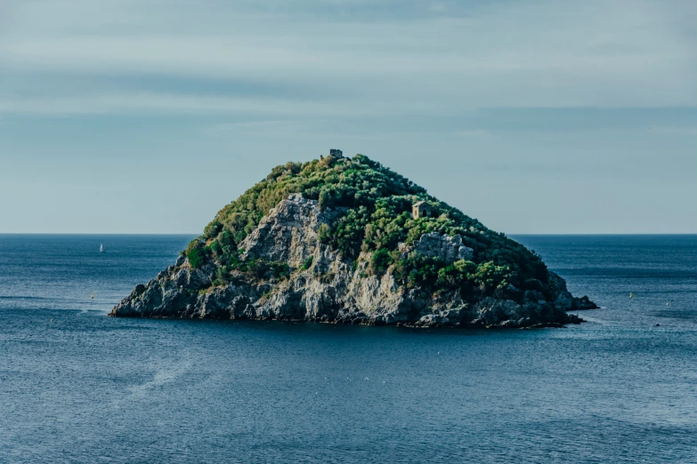 a rock island with a tower in the middle of blue water