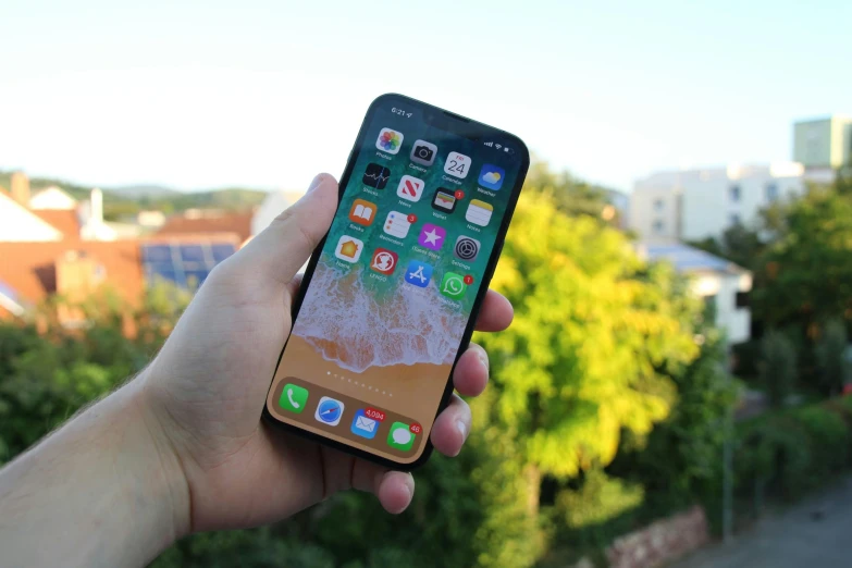 a hand holding up an iphone next to the view of trees