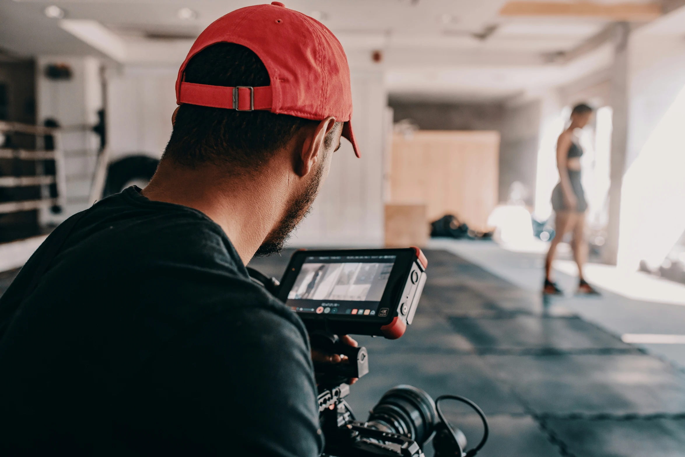 the man is filming a lady in a baseball hat