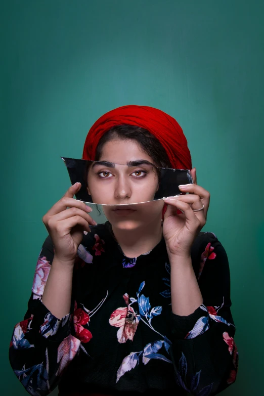 woman with red turban, green background holding up a mobile phone