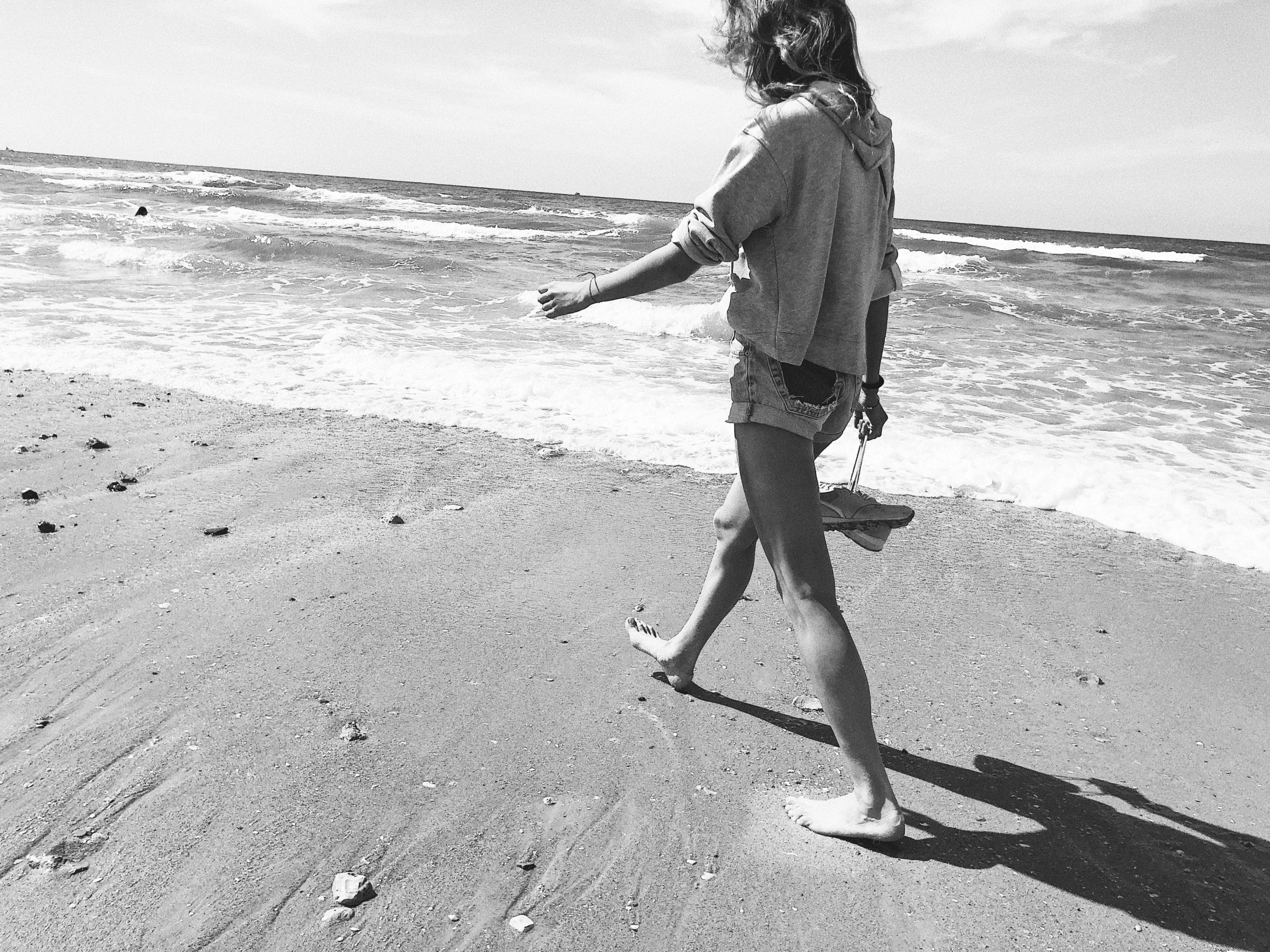 a woman is walking along the beach and throwing soing