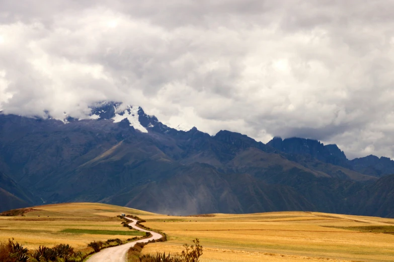 a lone road curves through the yellow and brown mountainous plains