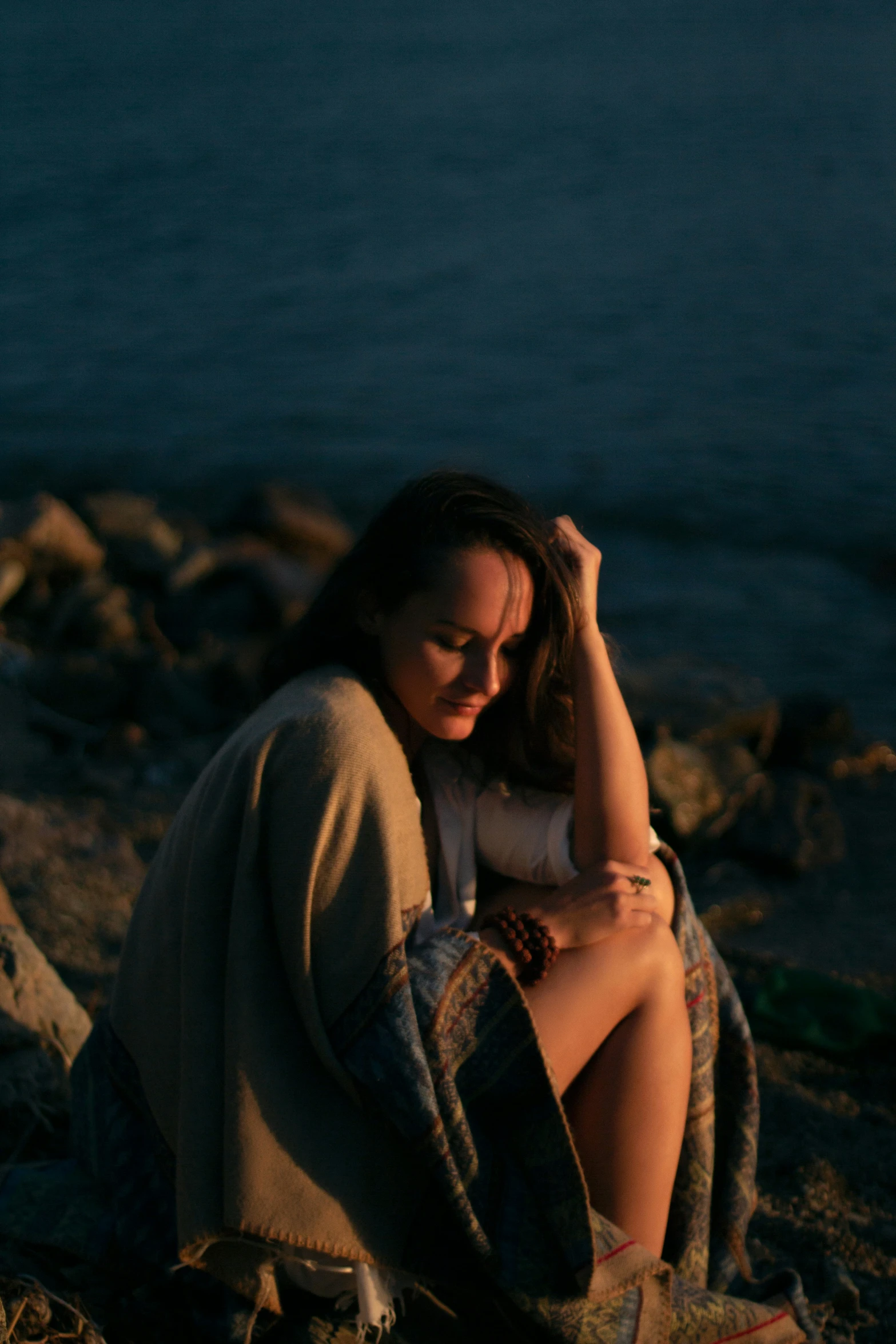 a woman sitting in the rocks next to the water