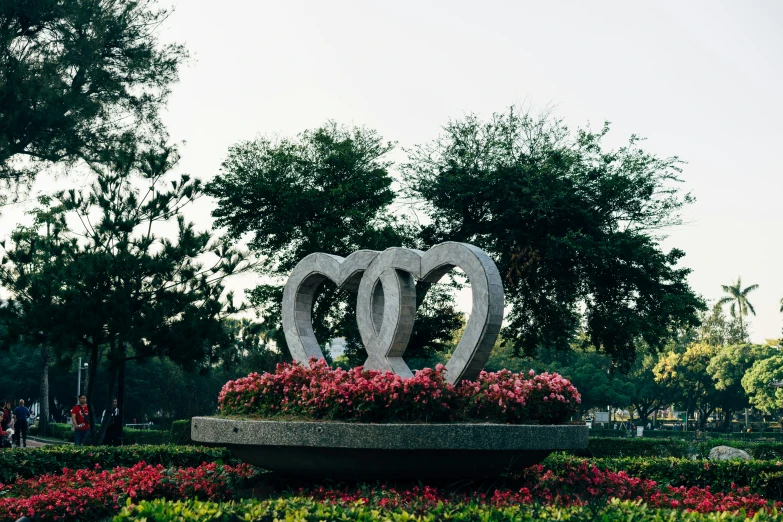 two circular sculptures in a garden surrounded by flowers