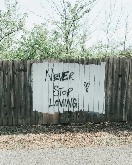 a fence covered in graffiti that reads never stop loving