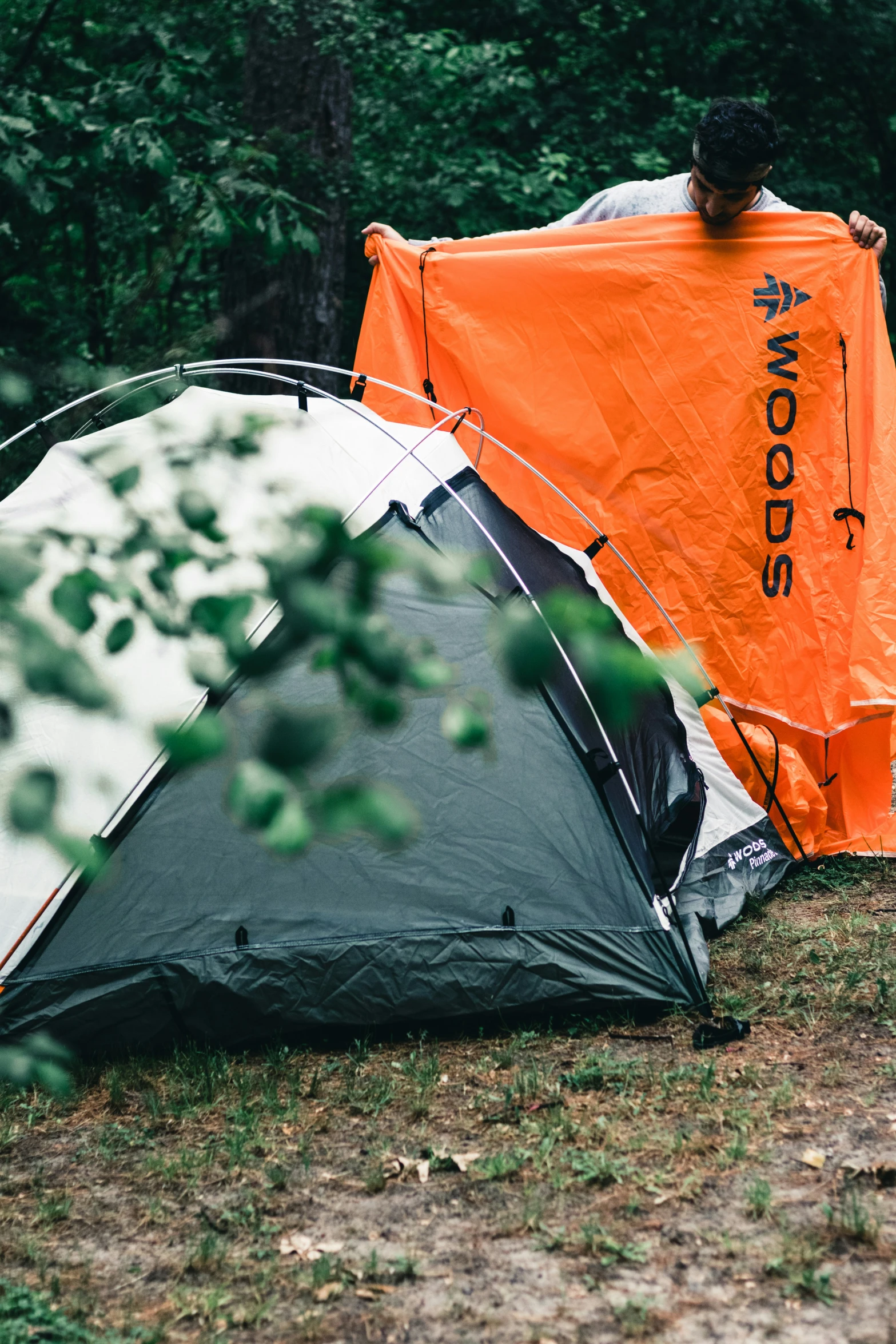 a man is holding an orange umbrella over some tents