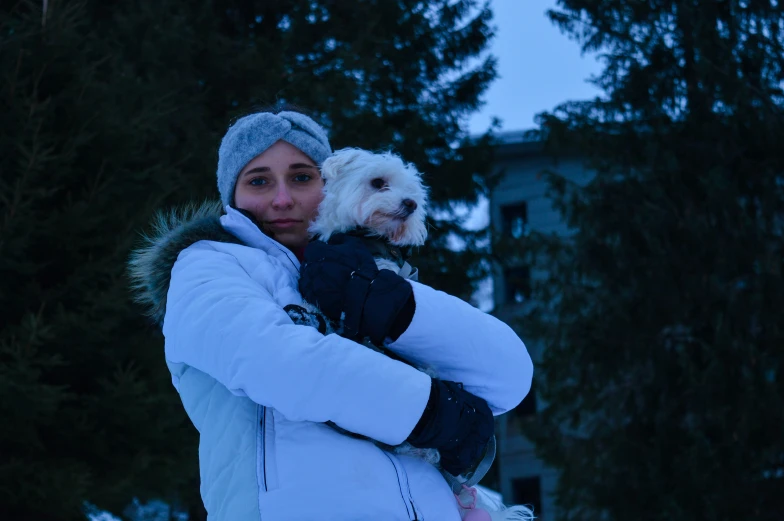 a young woman is holding her dog while outside in the snow