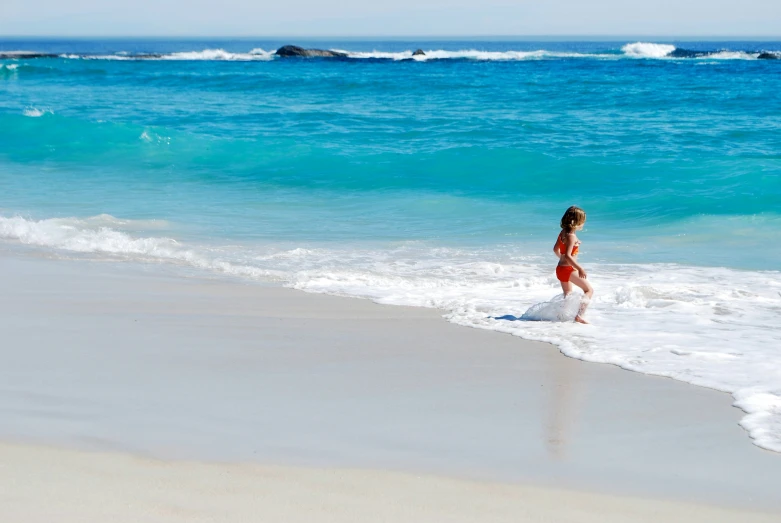 the child is walking into the water at the beach