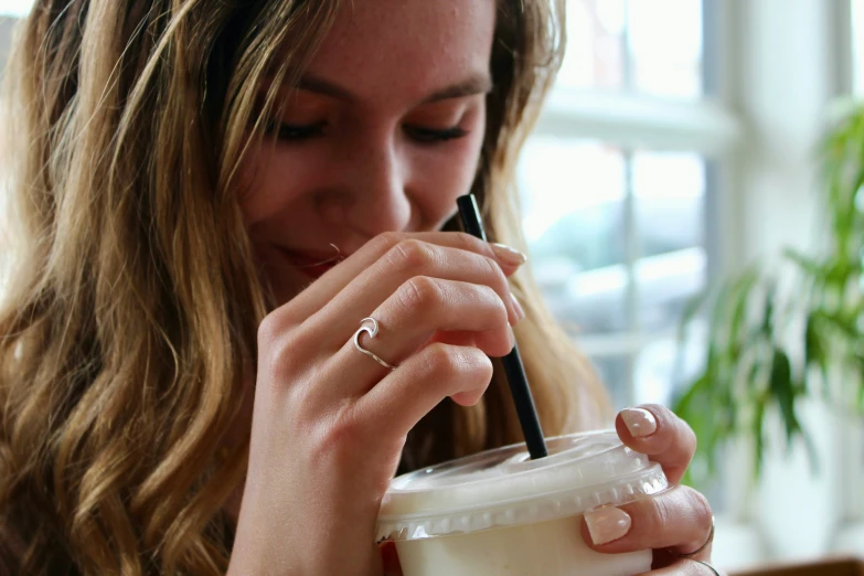 a woman holding onto a straw and looking into a drink