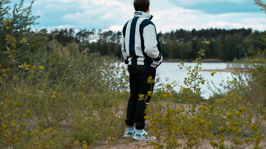 a man in striped jacket looking over a lake