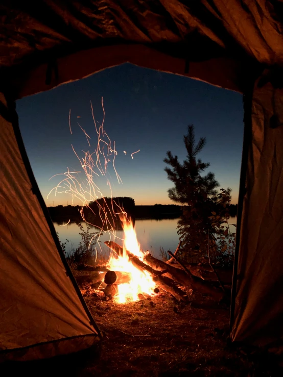 a camp fire burns inside of a tent at night