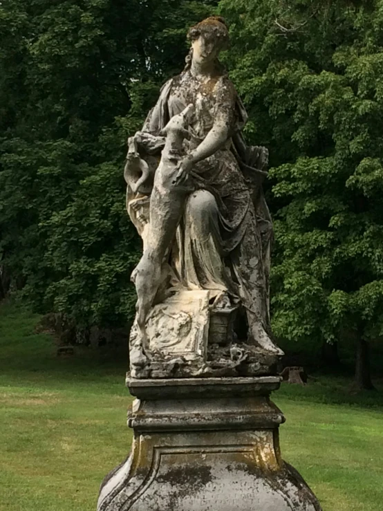 an old statue sits in a garden by the trees