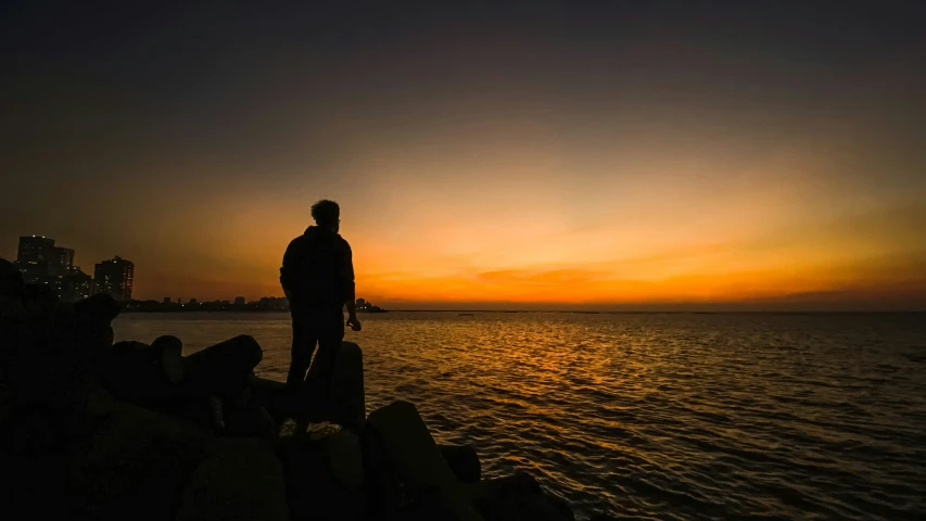 a person standing on a stone pier with a sunset background