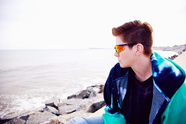 a boy sitting on rocks overlooking the ocean