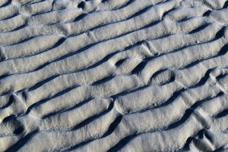 a beach scene with sand that has many tracks in it