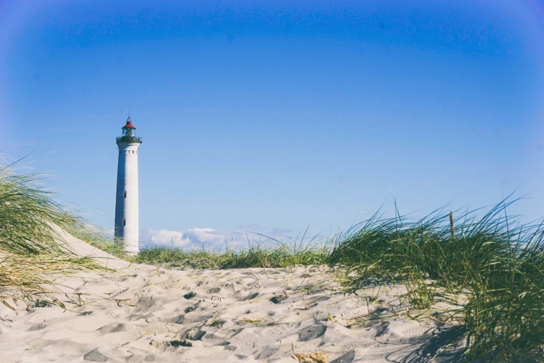 a tall light house sitting next to some grass