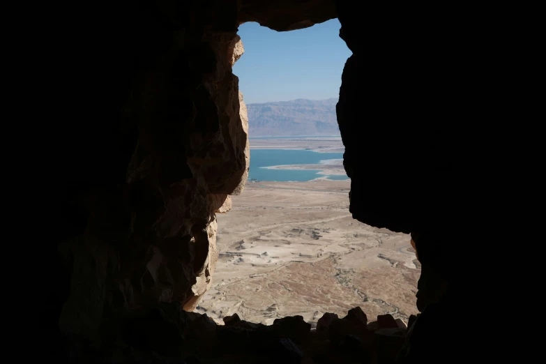 a window in a stone wall reveals an empty desert