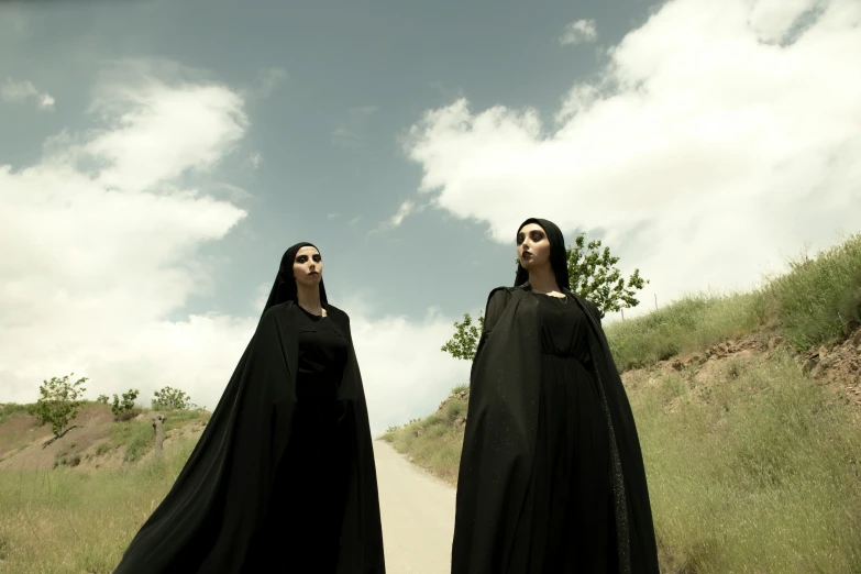two women are standing on the side of a dirt road