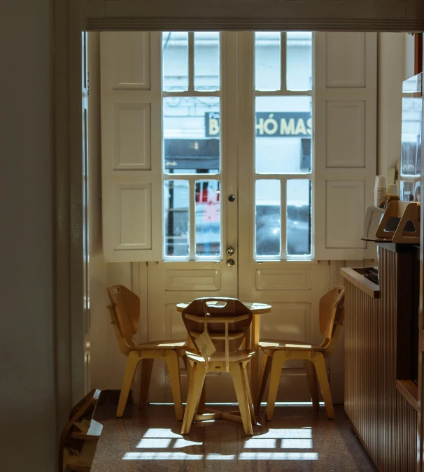 the inside of a small kitchen with three chairs, table and fridge