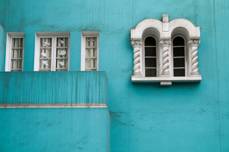 the corner of a blue building has an ornate window