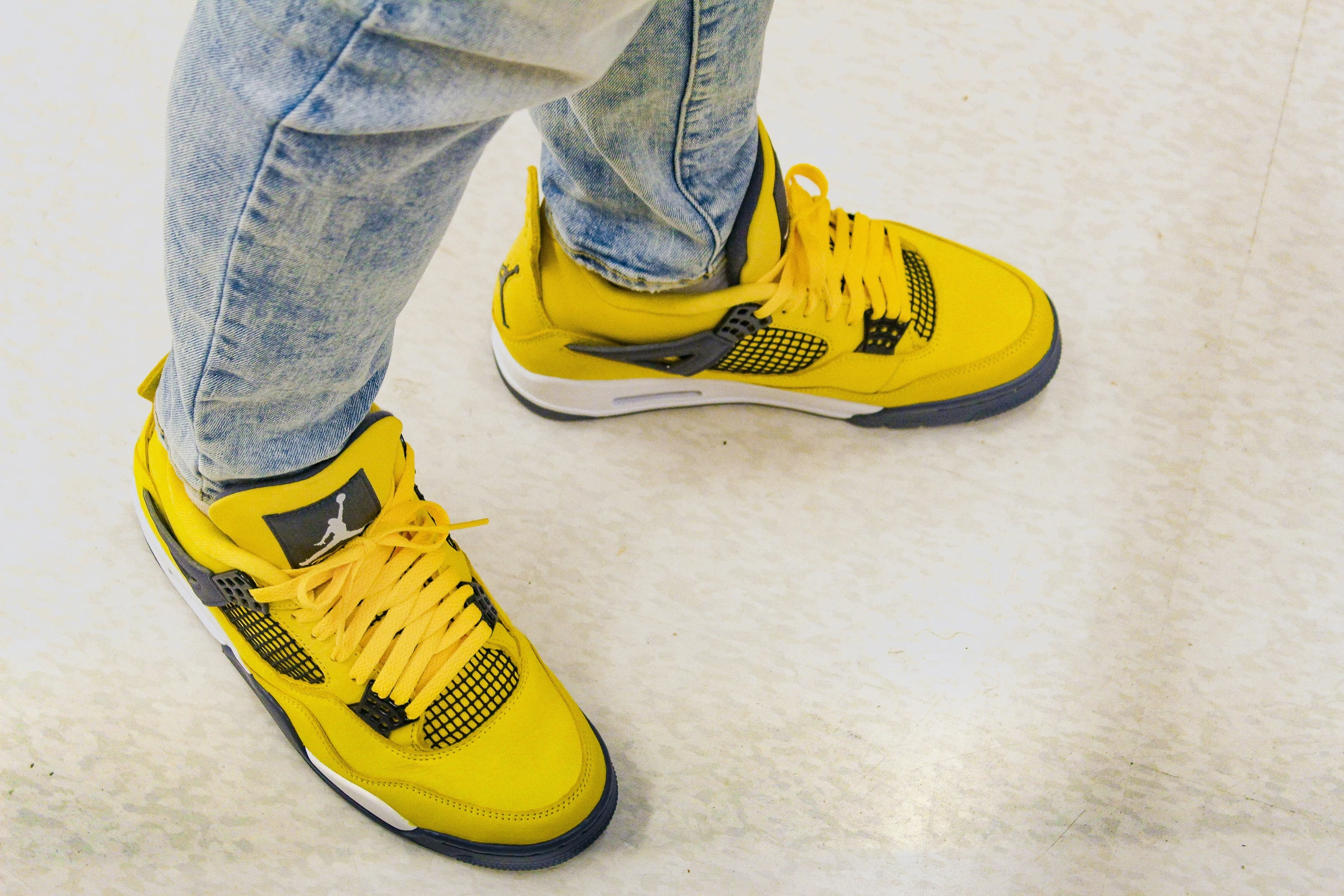 a person in jeans and sneakers is wearing yellow shoes