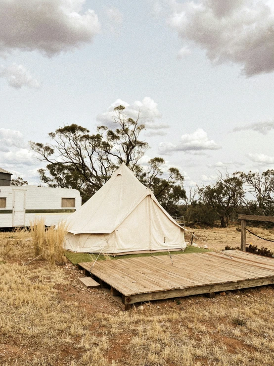 the white tent is on the grass next to a picnic table