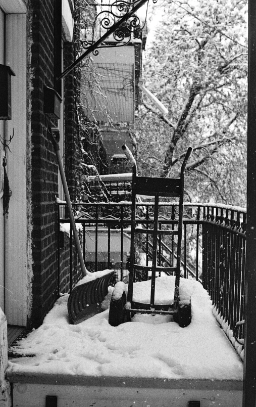 a stroller covered in snow sitting near a metal railing