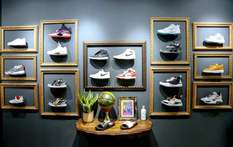 a wall displaying several pairs of nike sneakers in an antique gold frame