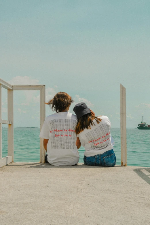 two children sitting together on top of a beach