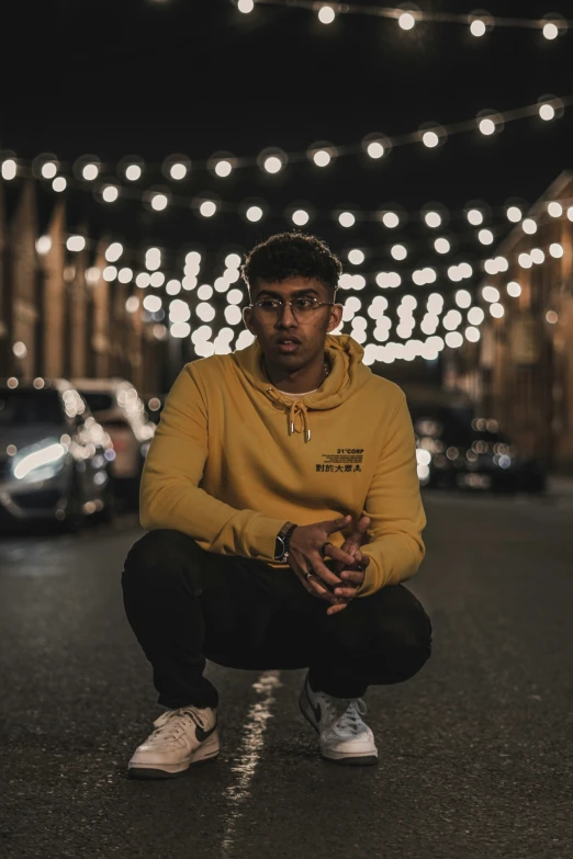 a man squatting down wearing a yellow sweatshirt