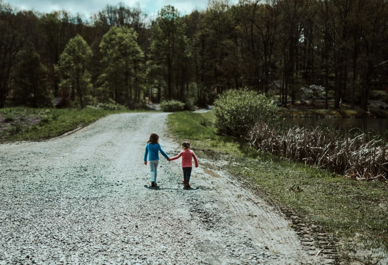 two children walking down a gravel road