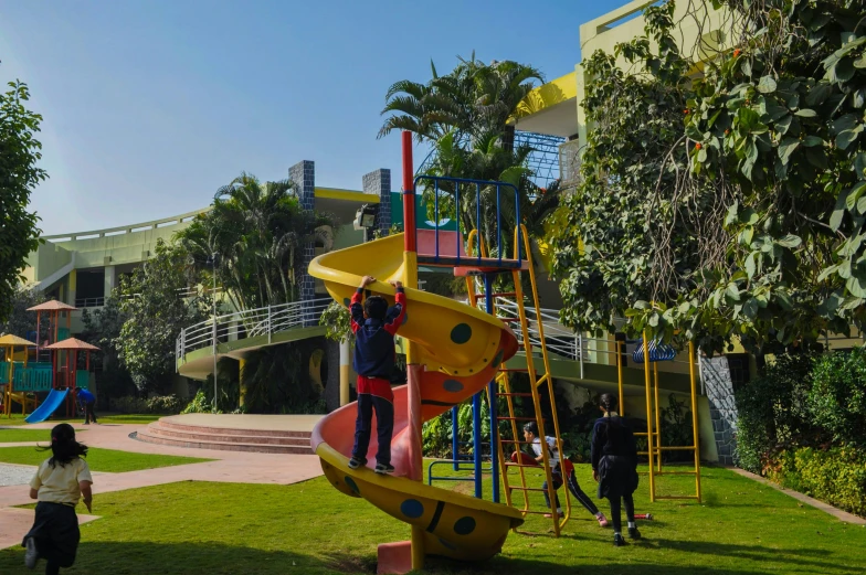 two children standing on top of a slide at a play ground