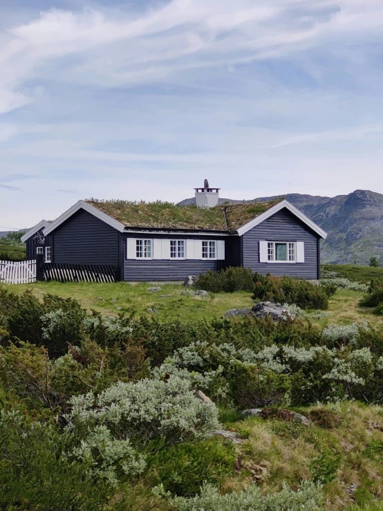 a small house with a green roof on a grass covered hill