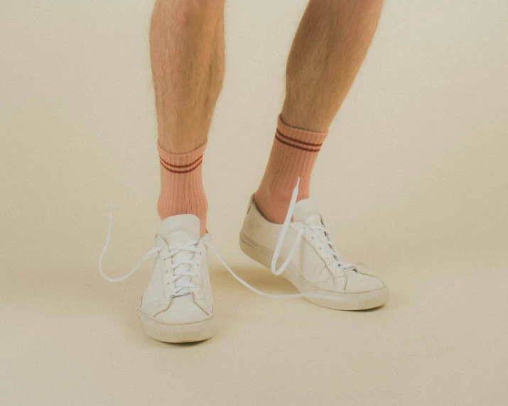 closeup s of a person wearing white tennis shoes and orange socks