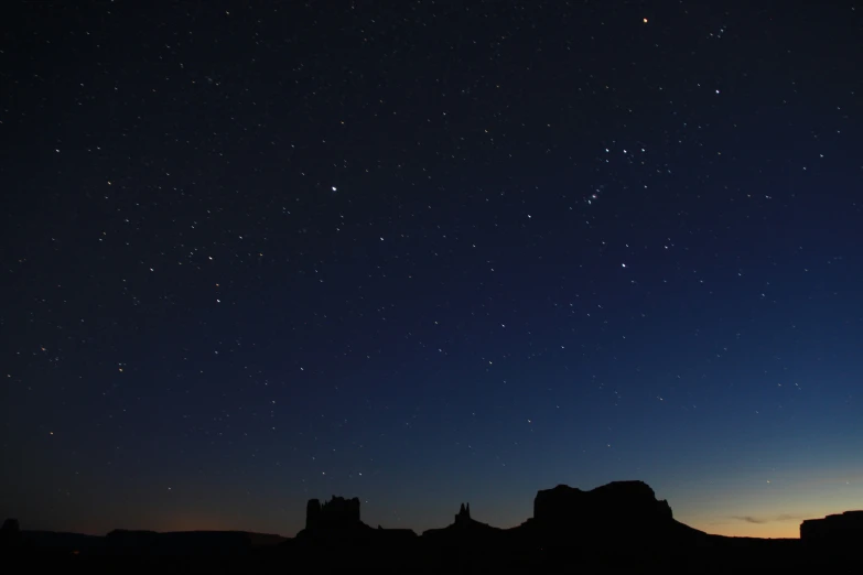 a sky full of stars with mountains in the background