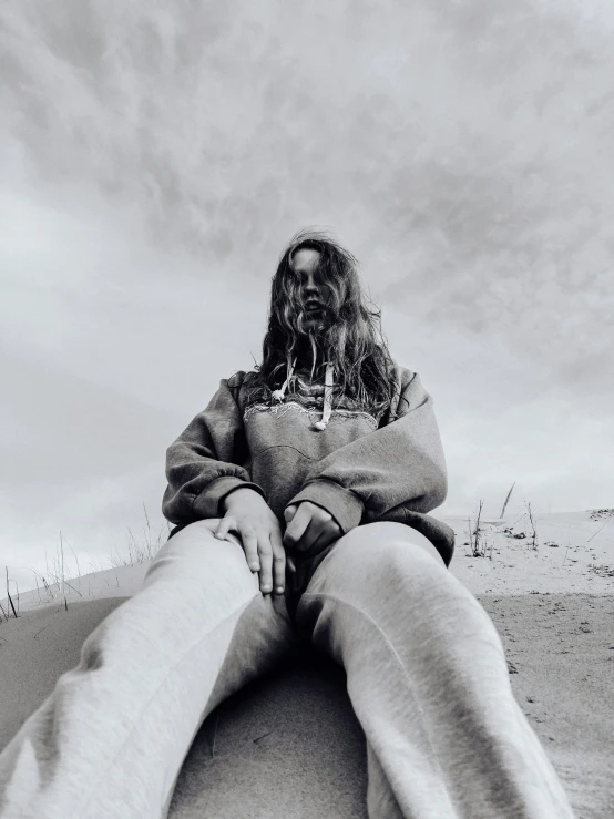 a young person sitting on top of a sandy beach