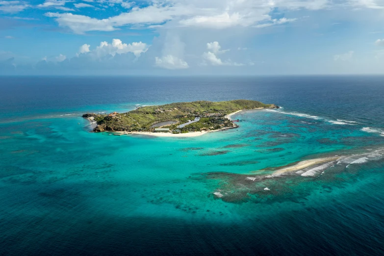 an island in the middle of blue water with clouds